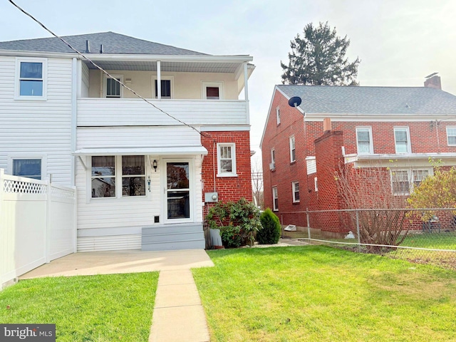 view of front of property featuring a balcony and a front yard