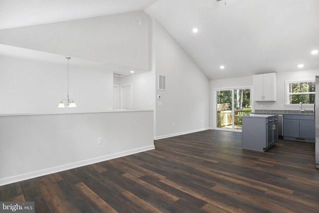 kitchen with dark wood-type flooring, high vaulted ceiling, hanging light fixtures, gray cabinets, and white cabinetry