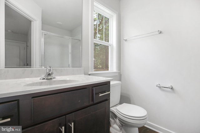 bathroom with a shower with door, vanity, and toilet