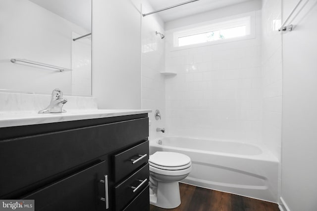 full bathroom with hardwood / wood-style floors, vanity, tiled shower / bath combo, and toilet