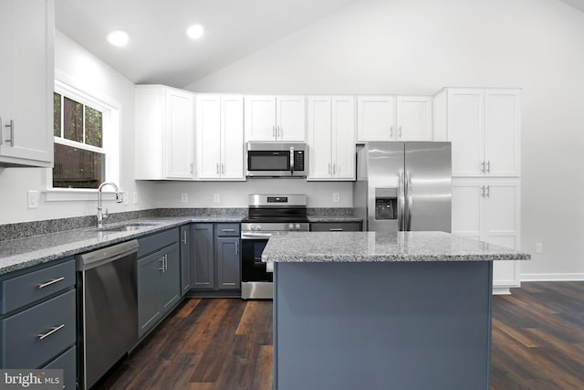 kitchen featuring dark hardwood / wood-style flooring, stainless steel appliances, white cabinets, a kitchen island, and lofted ceiling