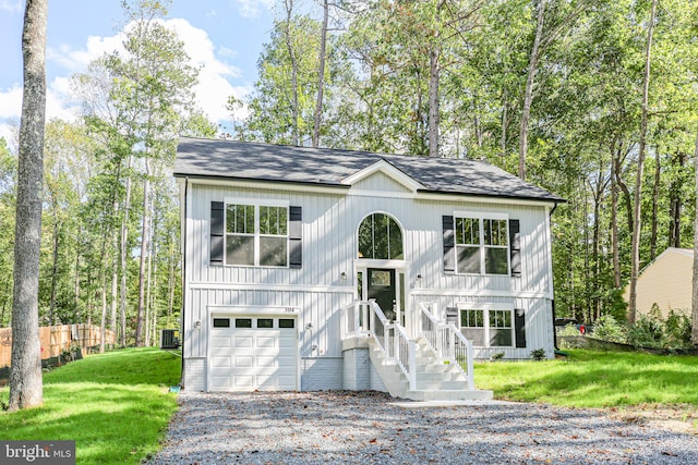 raised ranch with central AC unit, a front yard, and a garage