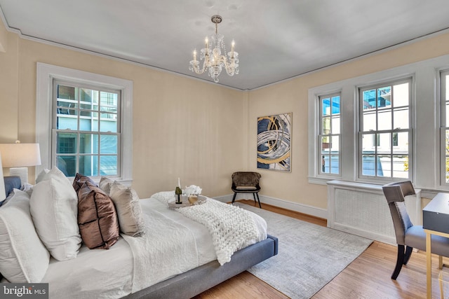 bedroom featuring multiple windows, a chandelier, and light wood-type flooring