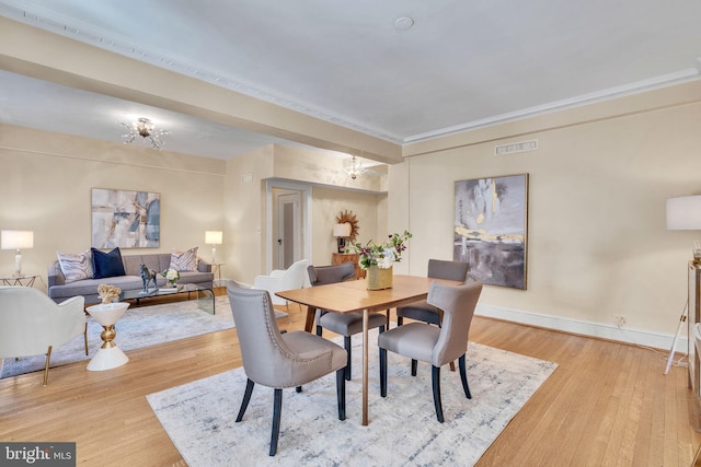 dining room with crown molding and light hardwood / wood-style floors