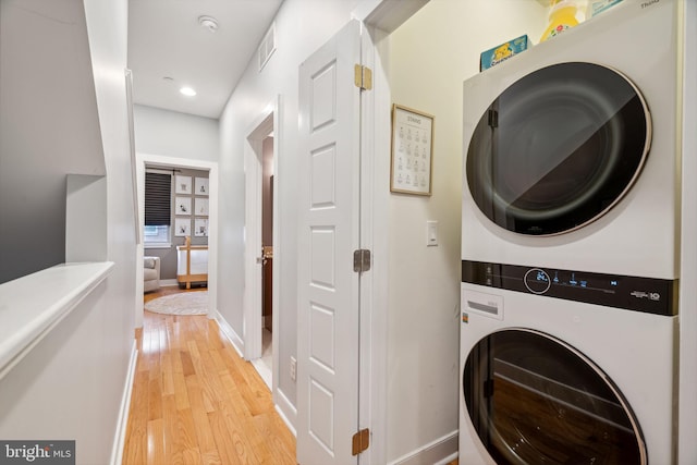 washroom with stacked washer / drying machine and light wood-type flooring