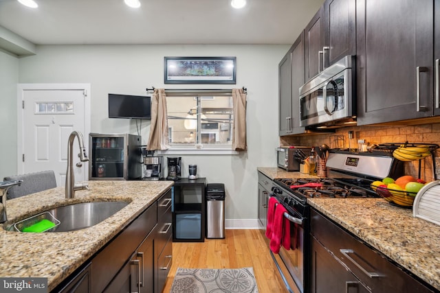 kitchen featuring light hardwood / wood-style floors, stainless steel appliances, light stone countertops, and tasteful backsplash