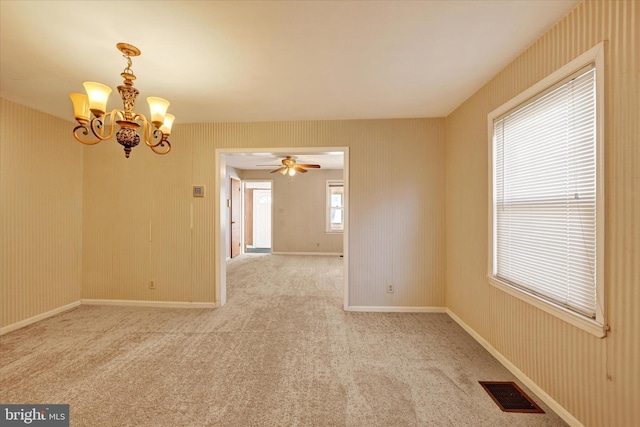 carpeted empty room with a notable chandelier