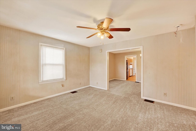 unfurnished room with ceiling fan and light carpet