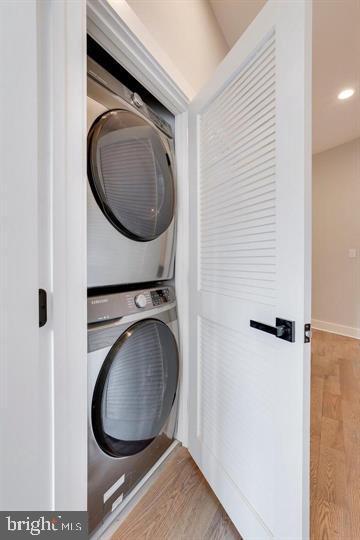 laundry area featuring light hardwood / wood-style flooring and stacked washer / drying machine