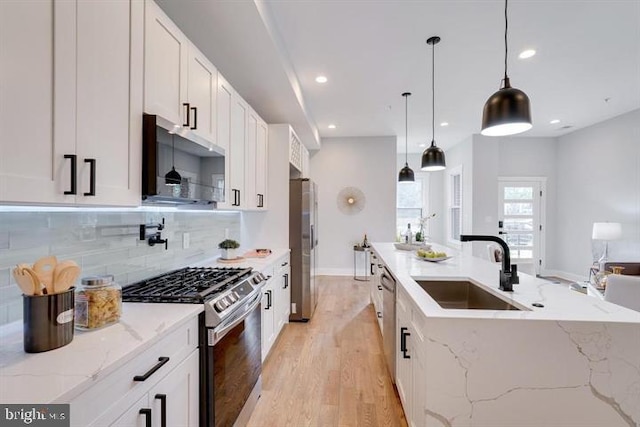 kitchen with stainless steel appliances, light stone countertops, pendant lighting, light hardwood / wood-style floors, and white cabinets