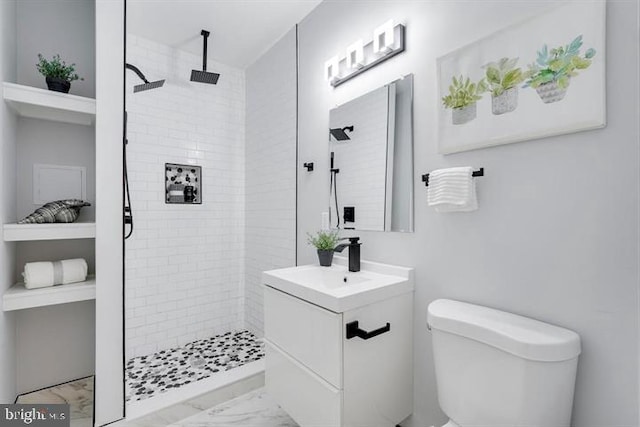 bathroom featuring tiled shower, toilet, and vanity