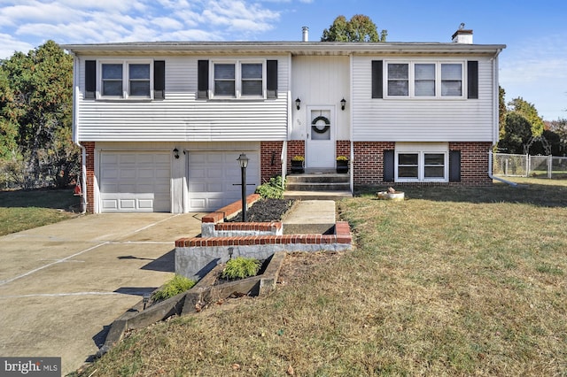 raised ranch featuring a garage and a front lawn