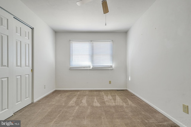 spare room with light colored carpet and ceiling fan