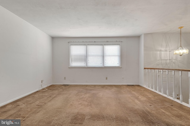 carpeted spare room with a chandelier