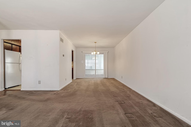 carpeted empty room featuring a notable chandelier