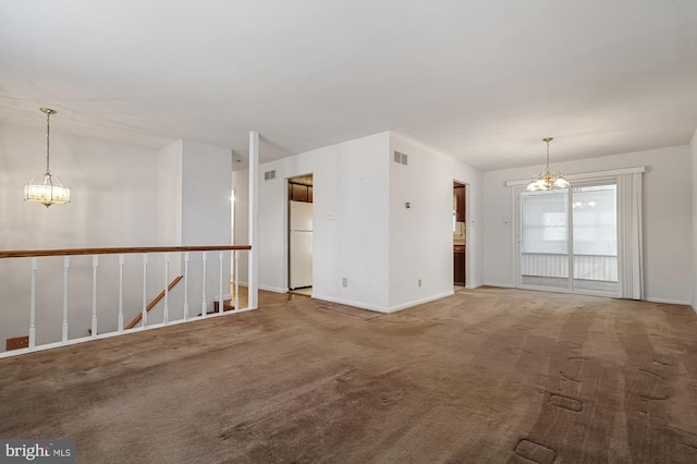 carpeted spare room featuring a notable chandelier