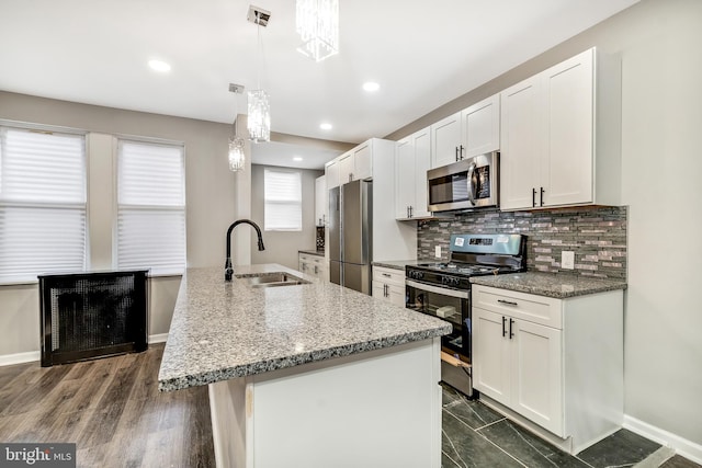 kitchen featuring pendant lighting, sink, an island with sink, appliances with stainless steel finishes, and dark hardwood / wood-style flooring