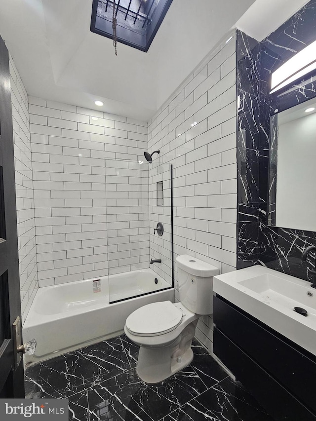 full bathroom featuring vanity, toilet, tiled shower / bath, and tile walls