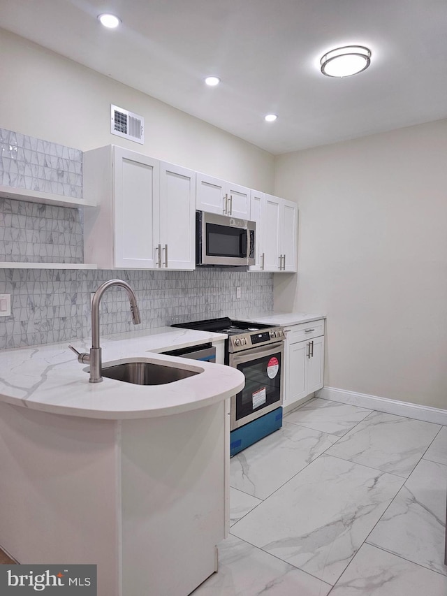 kitchen with backsplash, white cabinets, sink, light stone countertops, and appliances with stainless steel finishes