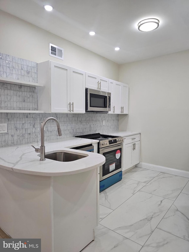 kitchen featuring decorative backsplash, appliances with stainless steel finishes, light stone countertops, sink, and white cabinets