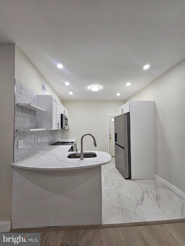 kitchen with kitchen peninsula, sink, light wood-type flooring, white cabinetry, and stainless steel appliances