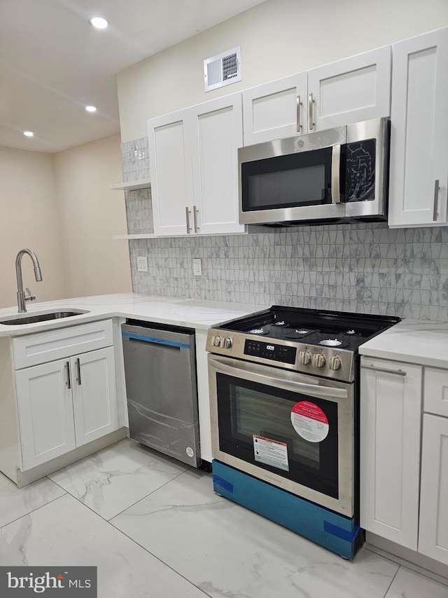 kitchen with white cabinets, backsplash, sink, and appliances with stainless steel finishes