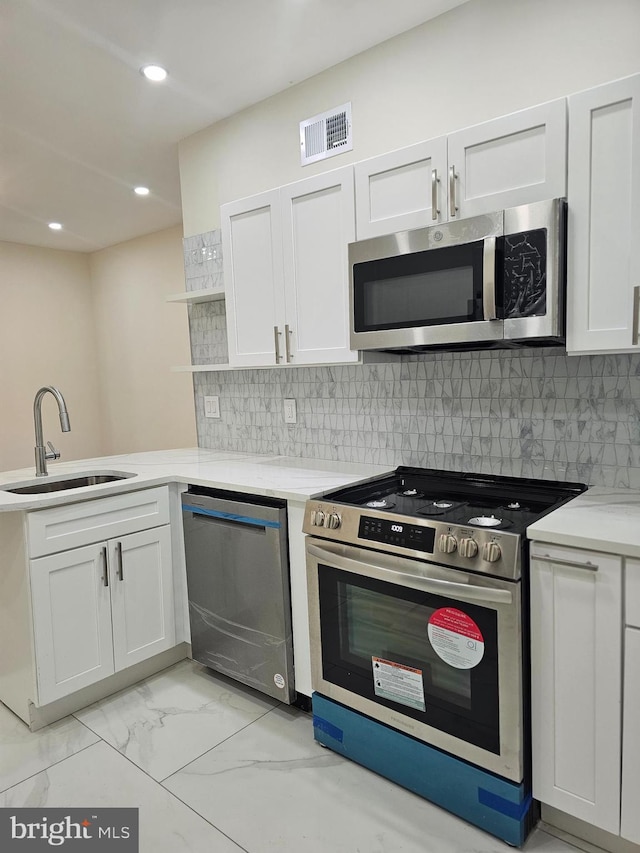 kitchen featuring white cabinets, backsplash, sink, and appliances with stainless steel finishes