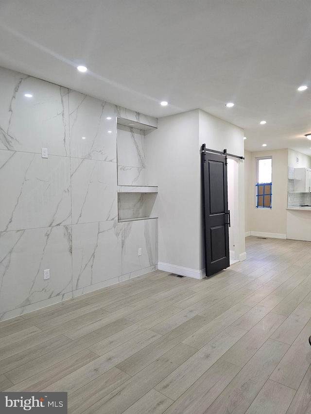 interior space featuring light wood-type flooring and a barn door