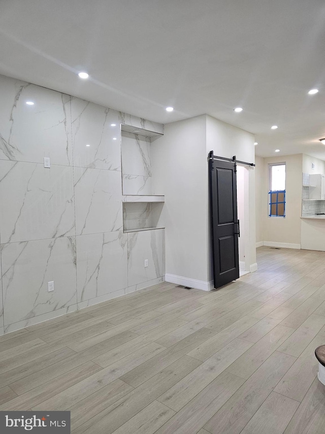 basement featuring a barn door and light hardwood / wood-style flooring