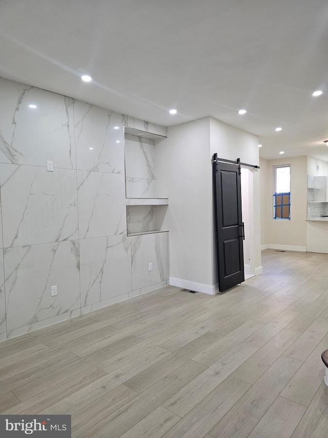 basement with a barn door and light wood-type flooring