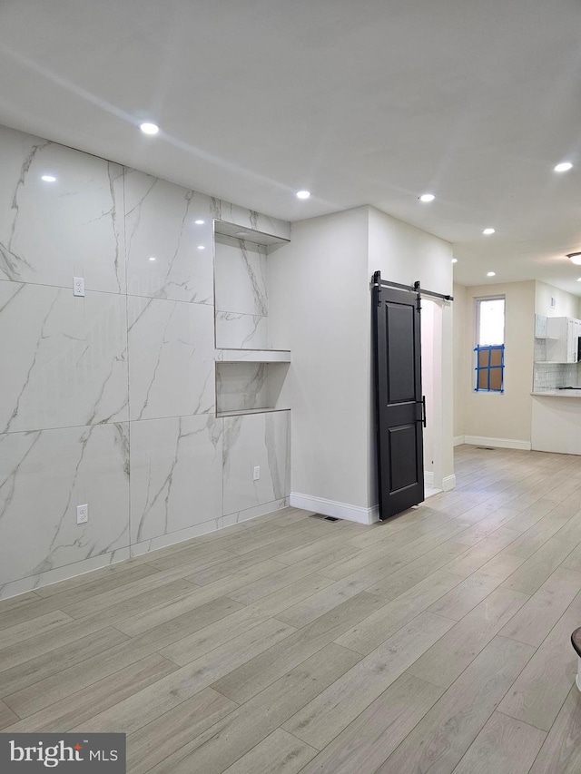 interior space with a barn door and light hardwood / wood-style floors