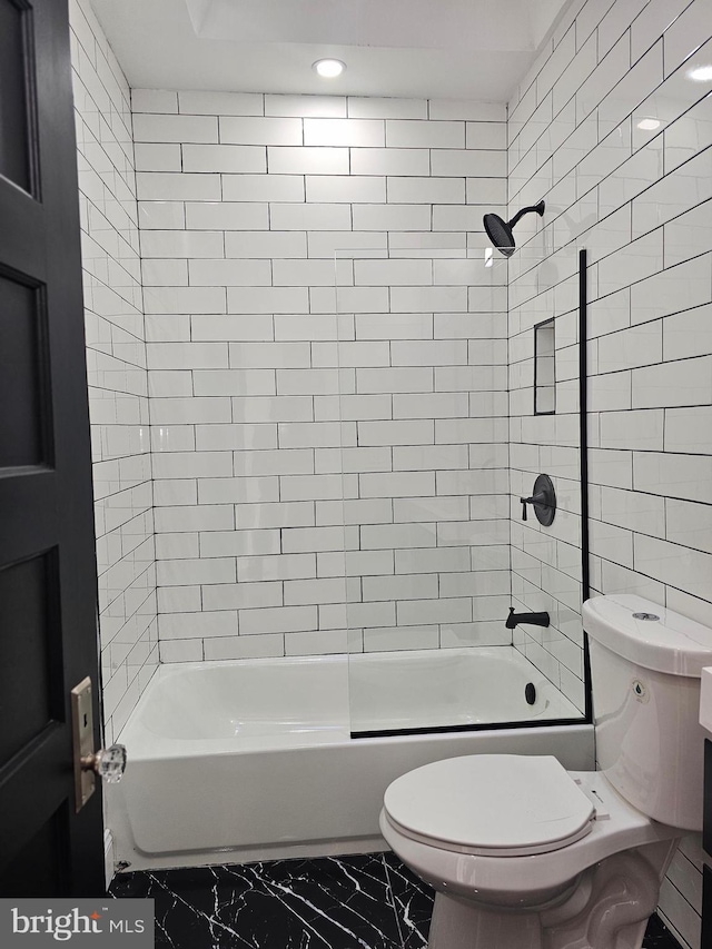 bathroom featuring tiled shower / bath combo and toilet