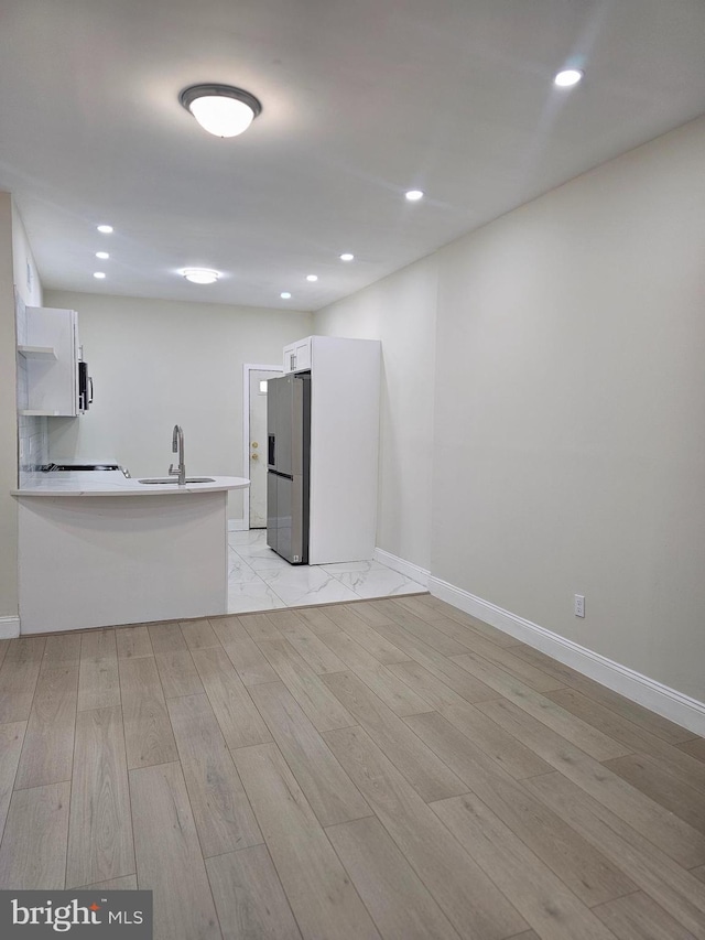 kitchen featuring white cabinetry, sink, kitchen peninsula, light hardwood / wood-style floors, and appliances with stainless steel finishes