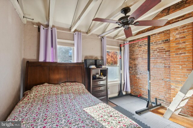 bedroom with ceiling fan, brick wall, and beamed ceiling