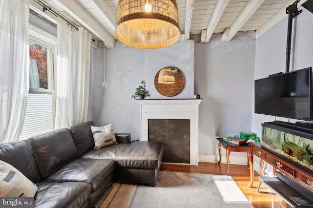 living room with beam ceiling, wood finished floors, a fireplace, and baseboards