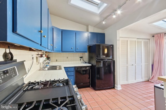 kitchen featuring blue cabinets, black appliances, a sink, tile countertops, and lofted ceiling with skylight