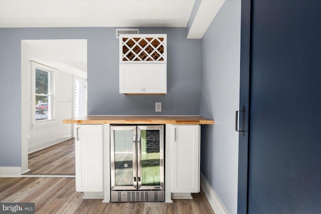 bar with wine cooler and light hardwood / wood-style flooring