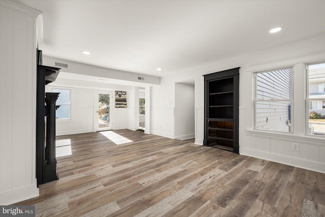 unfurnished living room with hardwood / wood-style floors and built in shelves