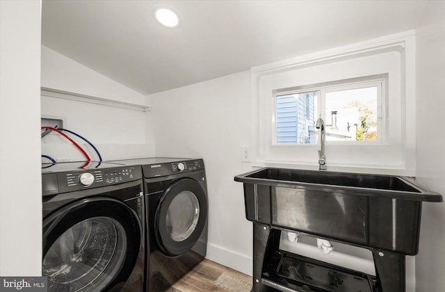 clothes washing area featuring washing machine and dryer, sink, and wood-type flooring