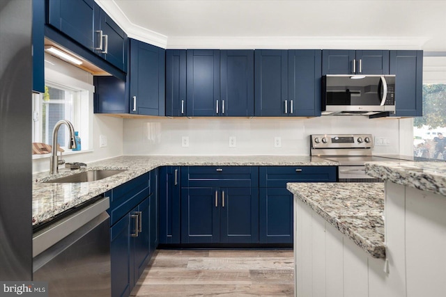 kitchen with appliances with stainless steel finishes, light hardwood / wood-style floors, blue cabinets, and sink