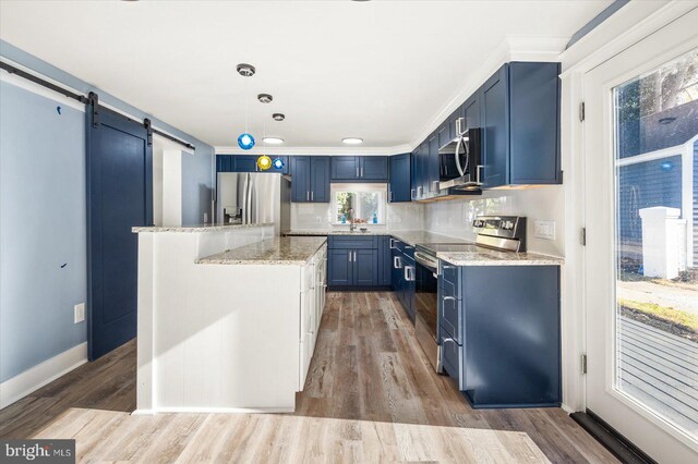 kitchen featuring a barn door, blue cabinetry, decorative light fixtures, light hardwood / wood-style floors, and stainless steel appliances