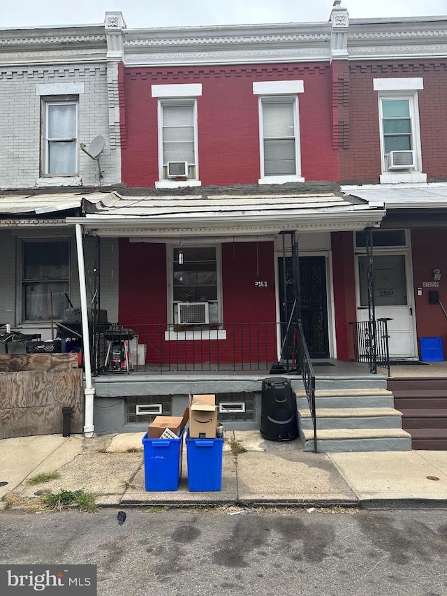 townhome / multi-family property featuring brick siding, a porch, and cooling unit
