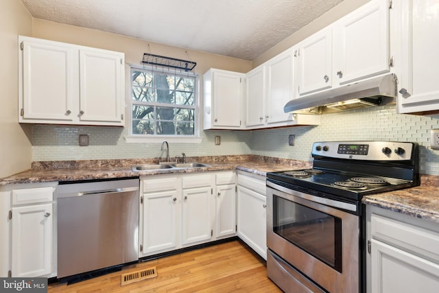 kitchen featuring appliances with stainless steel finishes, a textured ceiling, white cabinetry, and sink