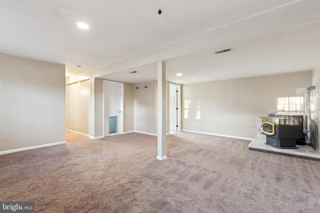 basement featuring a wood stove and carpet floors