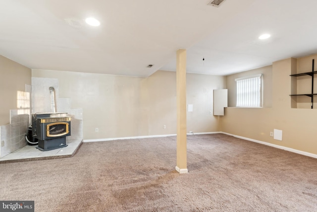 basement featuring carpet flooring and a wood stove