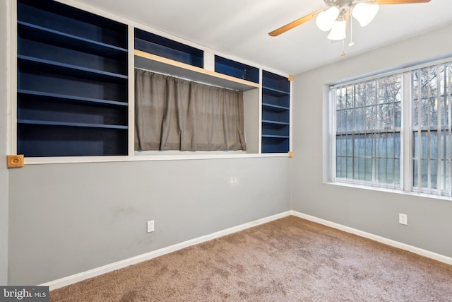 carpeted empty room with ceiling fan and built in features