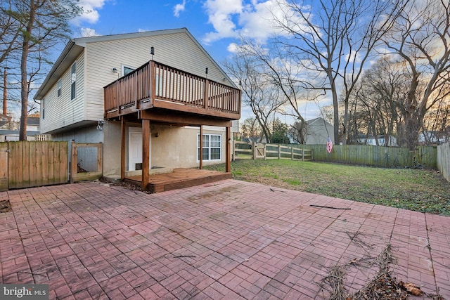 back of property with a lawn, a patio area, and a wooden deck