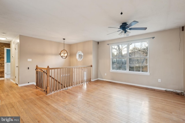 empty room featuring light hardwood / wood-style floors and ceiling fan with notable chandelier