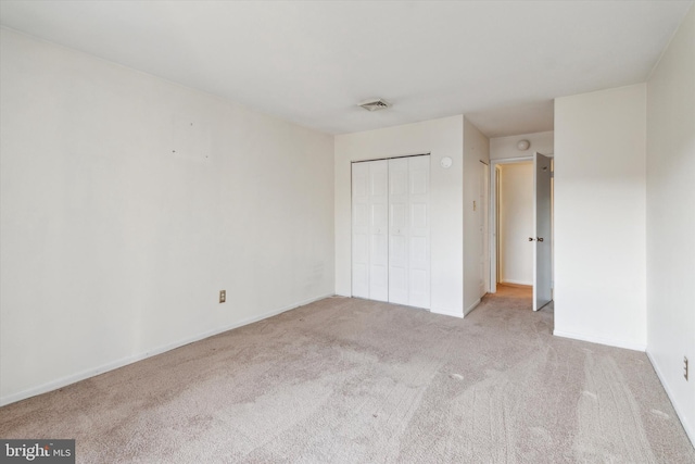 unfurnished bedroom with a closet and light carpet