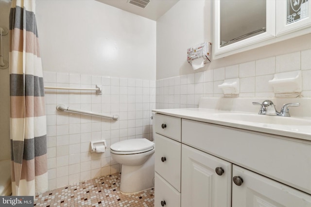 bathroom featuring toilet, tile patterned flooring, a shower with curtain, vanity, and tile walls